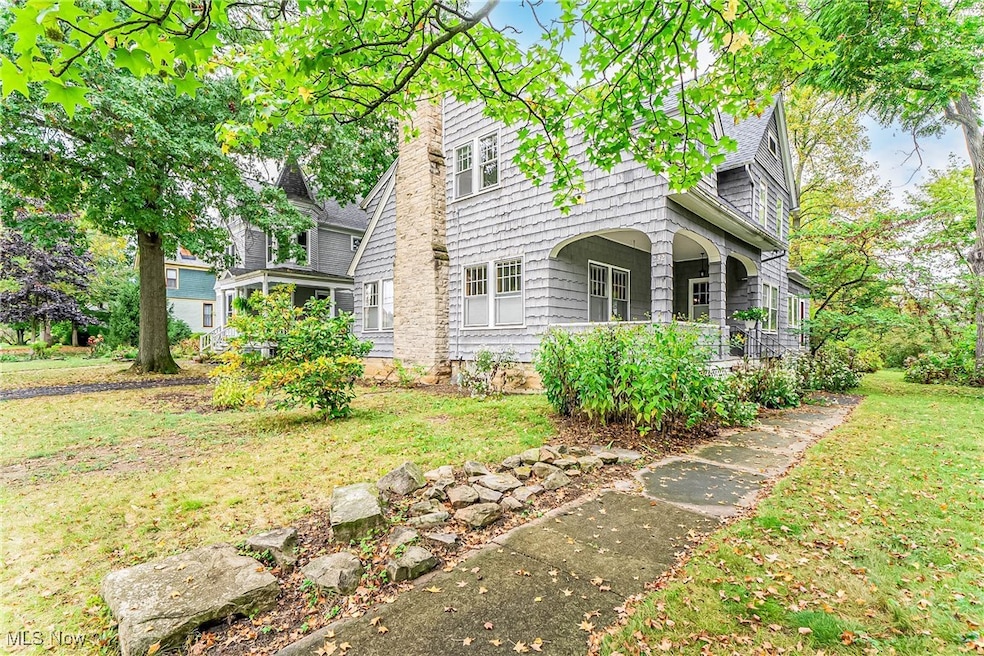 New England style home featuring a stone chimney, shingled siding, covered porch, and  front yard