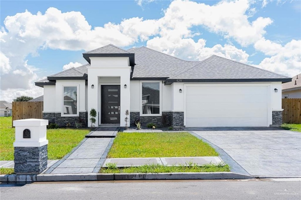 Prairie-style house with a garage, stone siding, fence, and decorative driveway