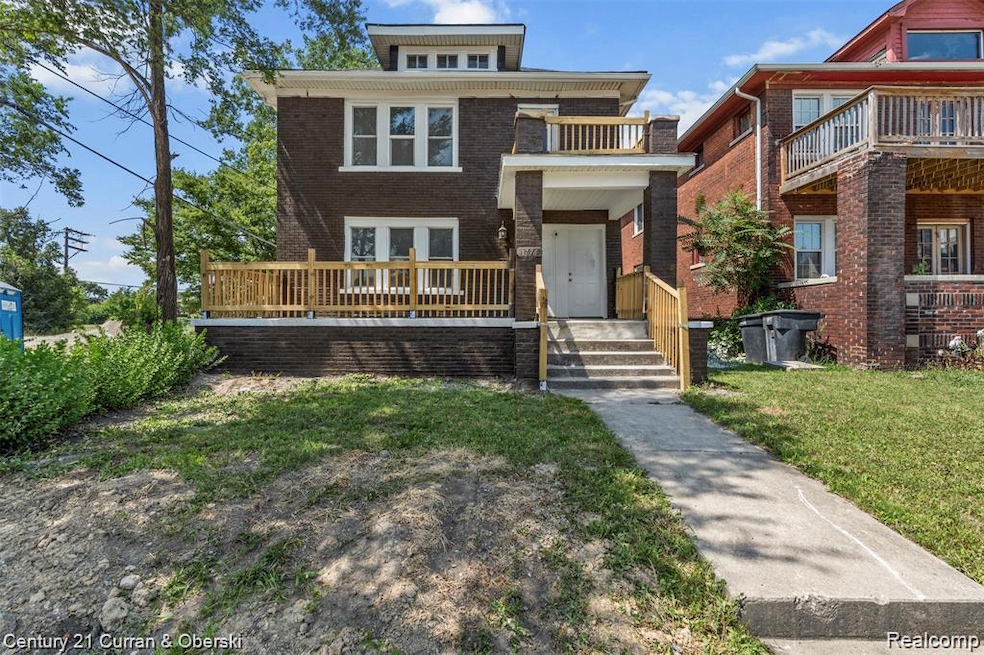 View of front facade featuring a front lawn, brick siding, and a balcony
