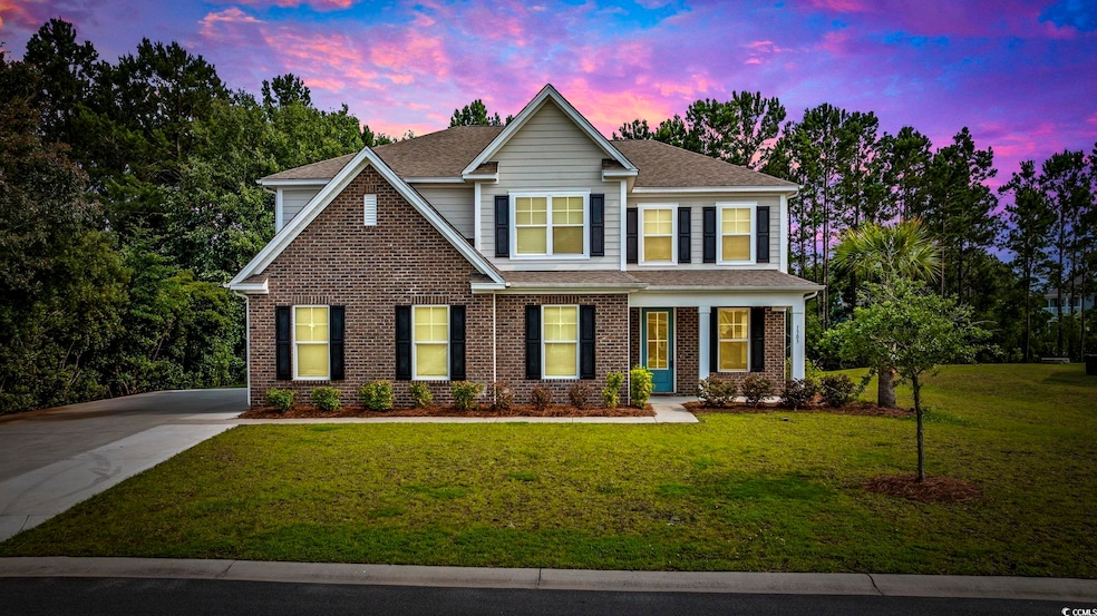 View of front facade with a shingled roof, a front lawn, and brick siding