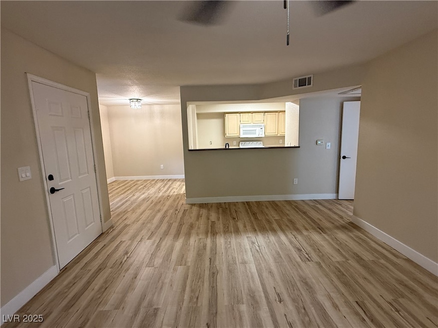 Unfurnished living room featuring baseboards, visible vents, and light wood-type flooring