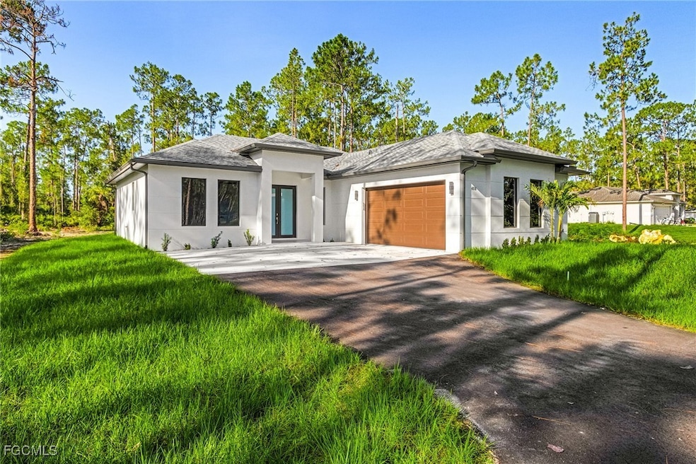 Prairie-style home with stucco siding, a front lawn, a garage, and driveway