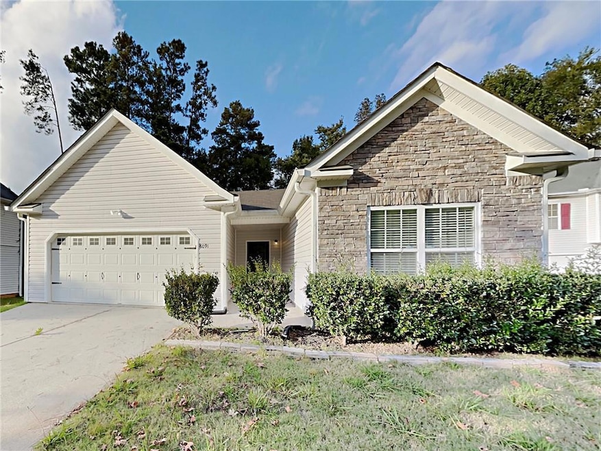 View of front facade featuring stone siding, a garage, and driveway