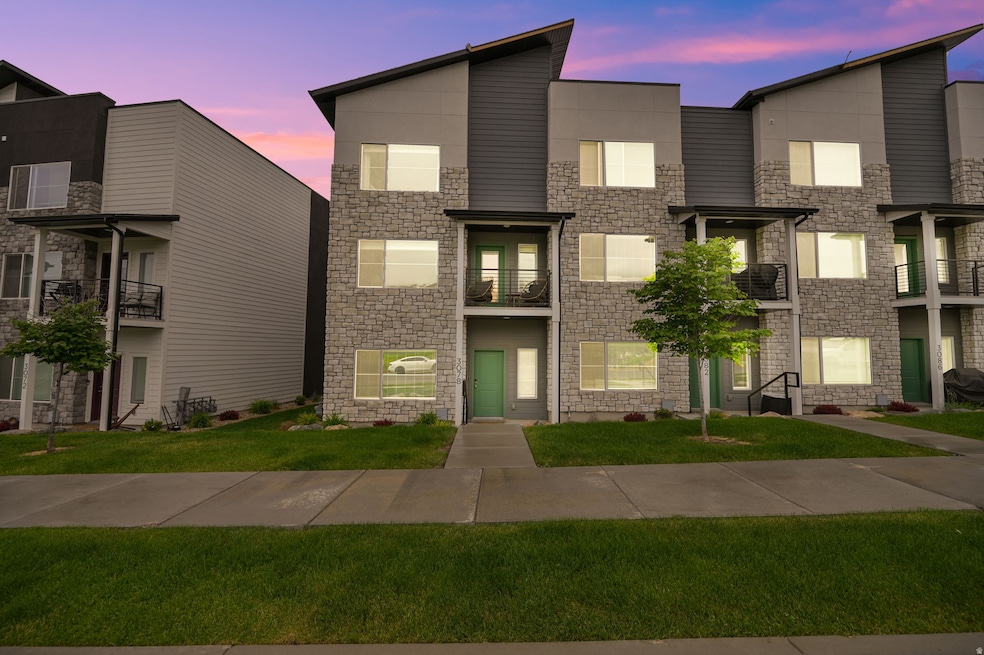 Contemporary house featuring a balcony, stone siding, and a front lawn