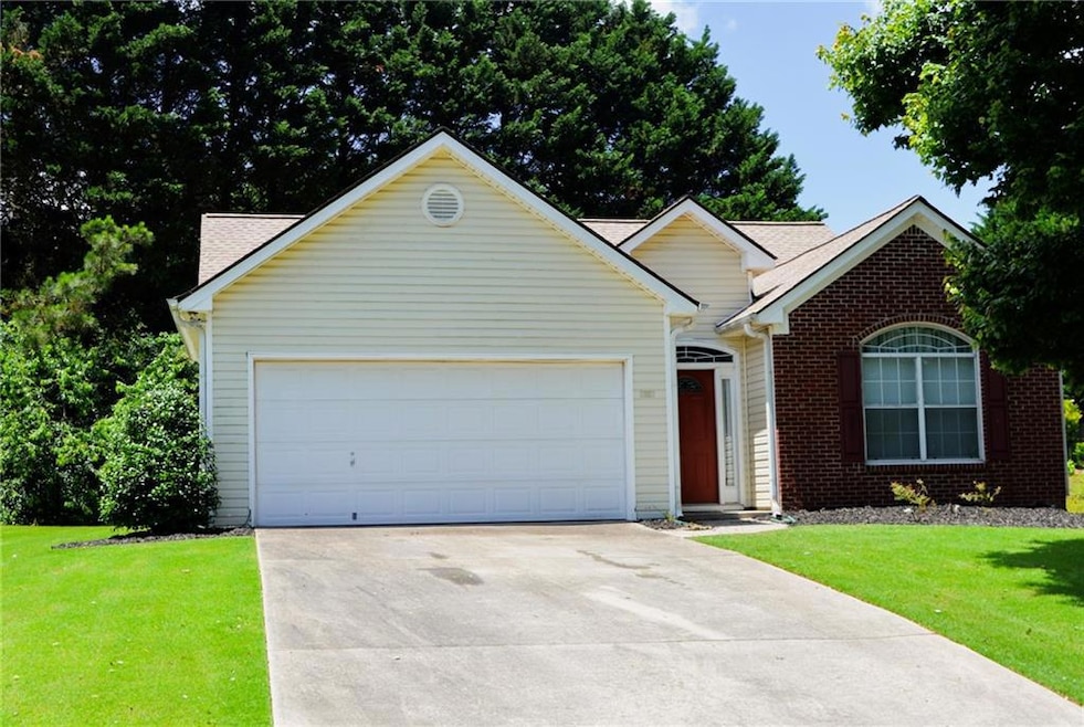 View of front facade with driveway, a garage, a front lawn, and brick siding