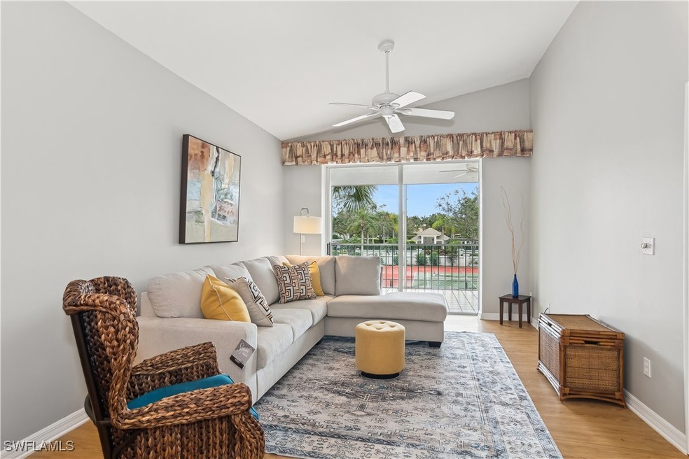 Living room featuring ceiling fan, light wood-type flooring, and vaulted ceiling
