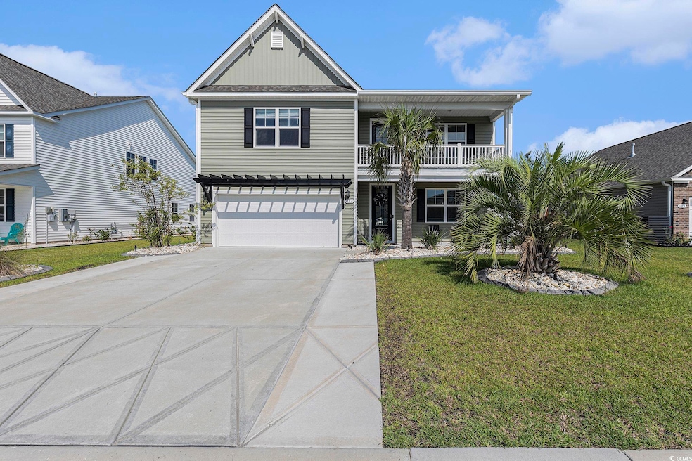 View of front facade featuring a balcony, concrete driveway, an attached garage, and a front yard