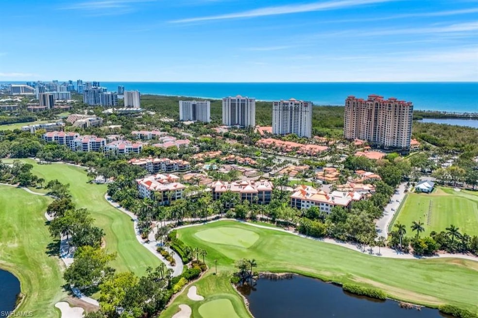 Drone / aerial view of a nearby body of water, a golf club, and apartment complex / building