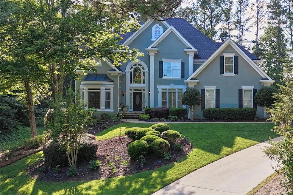 View of front of home featuring stucco siding, a front yard, and a shingled roof