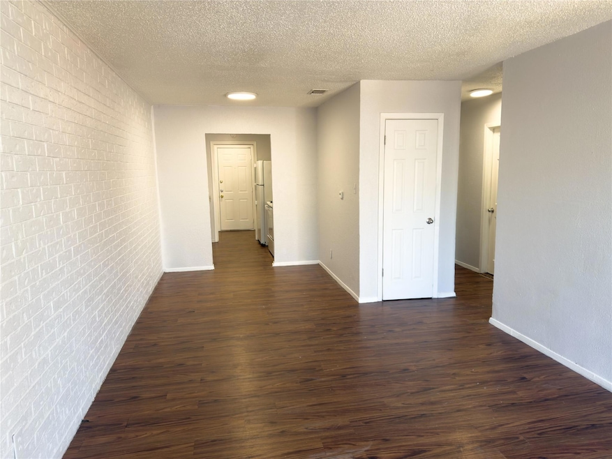 Corridor featuring brick wall, baseboards, and da