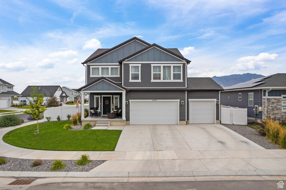 View of front of home with board and batten siding, driveway, an attached garage, a porch, and a gate