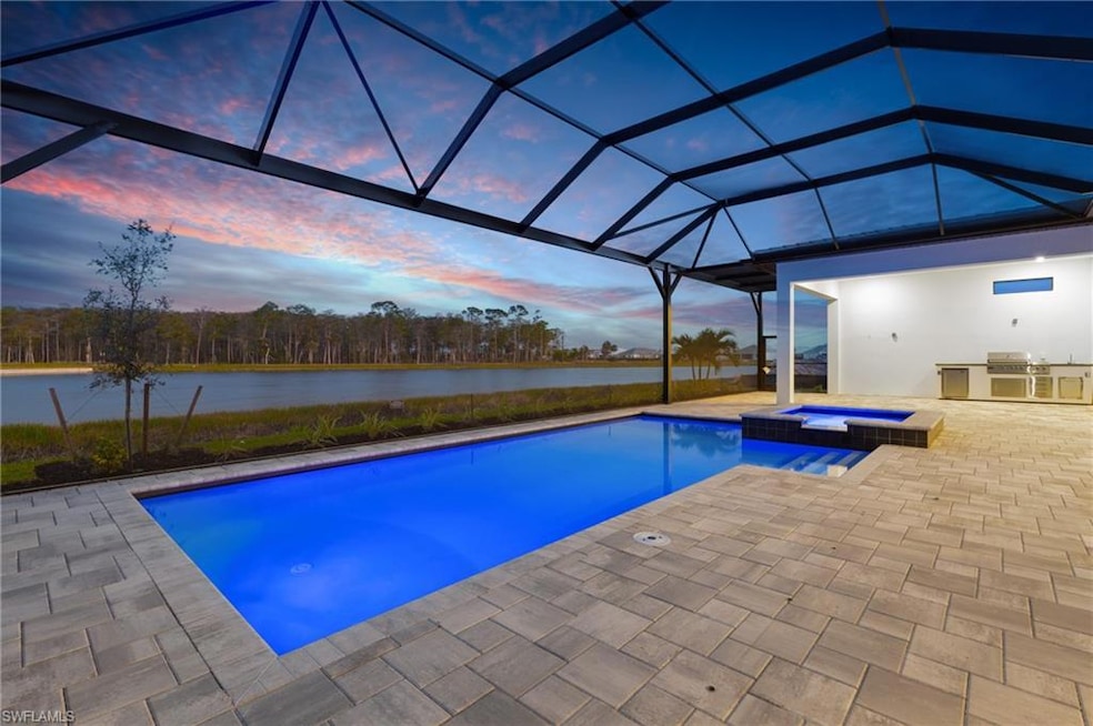View of swimming pool with exterior kitchen, a water view, a patio, a pool with connected hot tub, and glass enclosure