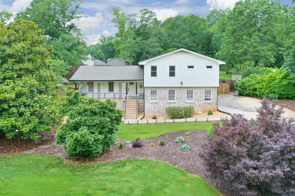 Tri-level home featuring covered porch and brick siding