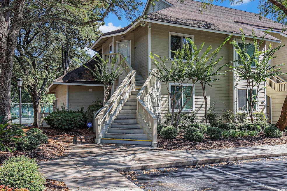 View of front of property featuring a balcony, roof with shingles, and stairs
