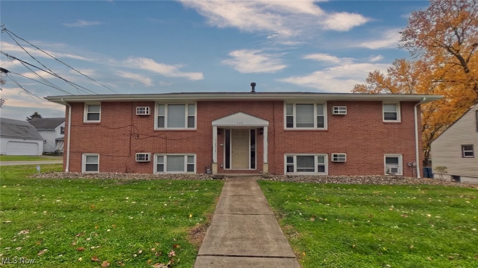 Raised ranch featuring brick siding and a front yard