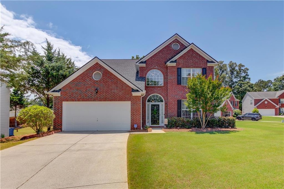 View of front of property with a front yard, brick siding, and an attached garage