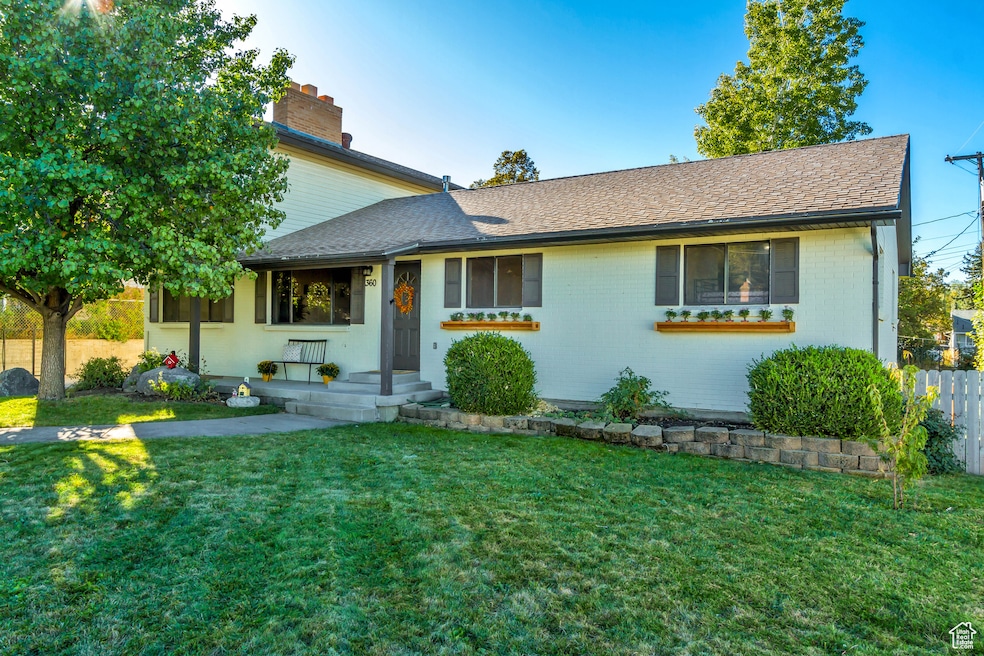 View of front of house with brick siding, roof with shingles, and a chimney