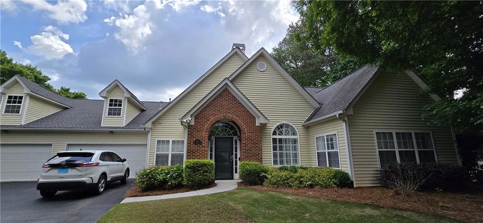 View of front facade featuring driveway, a chimney