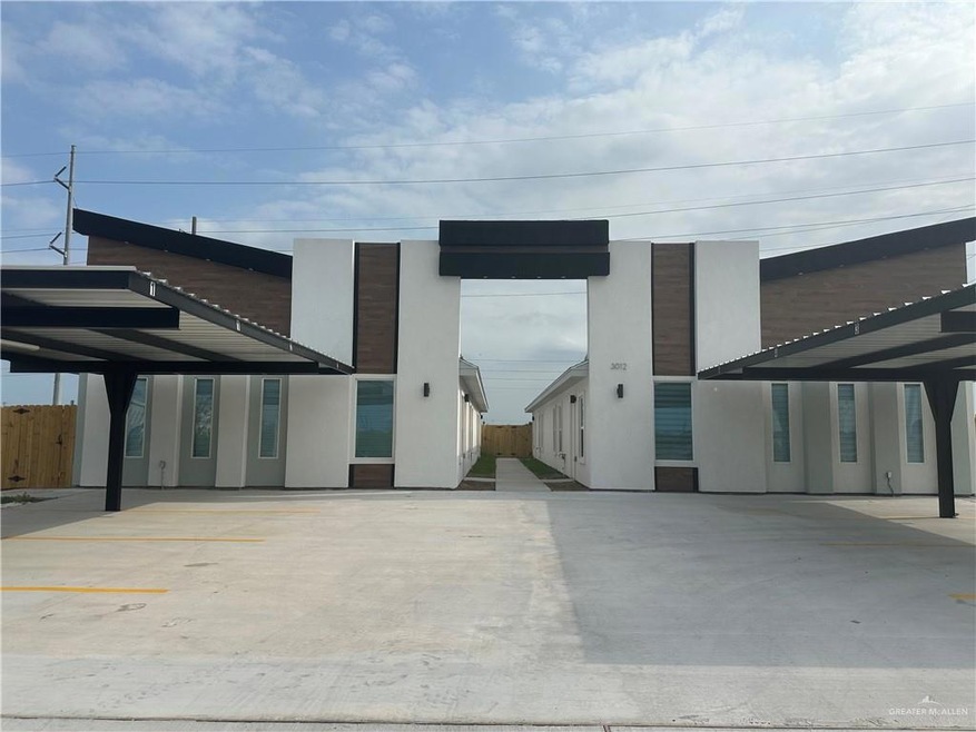 View of building exterior featuring fence and covered parking
