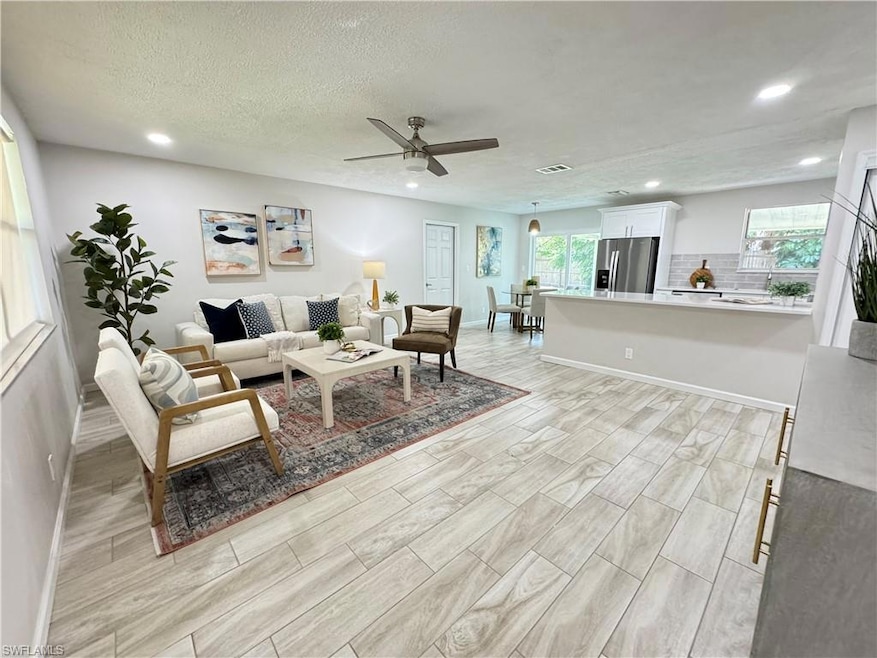 Living room featuring wood finish floors, a textured ceiling, ceiling fan, and recessed lighting