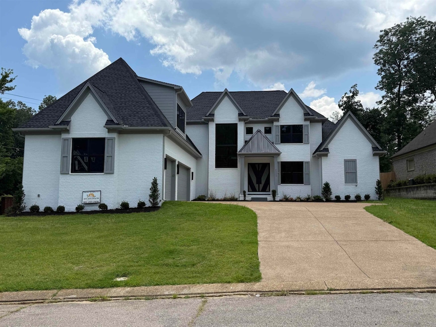 View of front of property with concrete driveway, brick siding, a front lawn, a garage, and a shingled roof