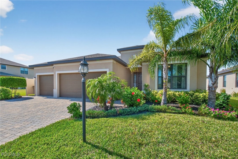 View of front facade featuring stucco siding, a front yard, a garage, and decorative driveway