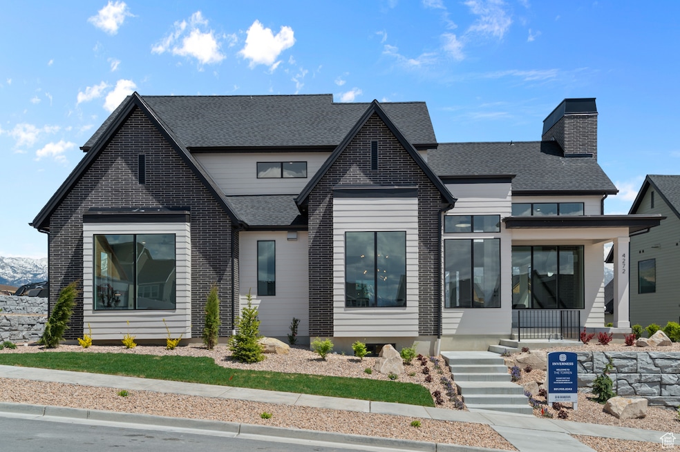 View of front of home featuring a shingled roof, a chimney, and covered porch