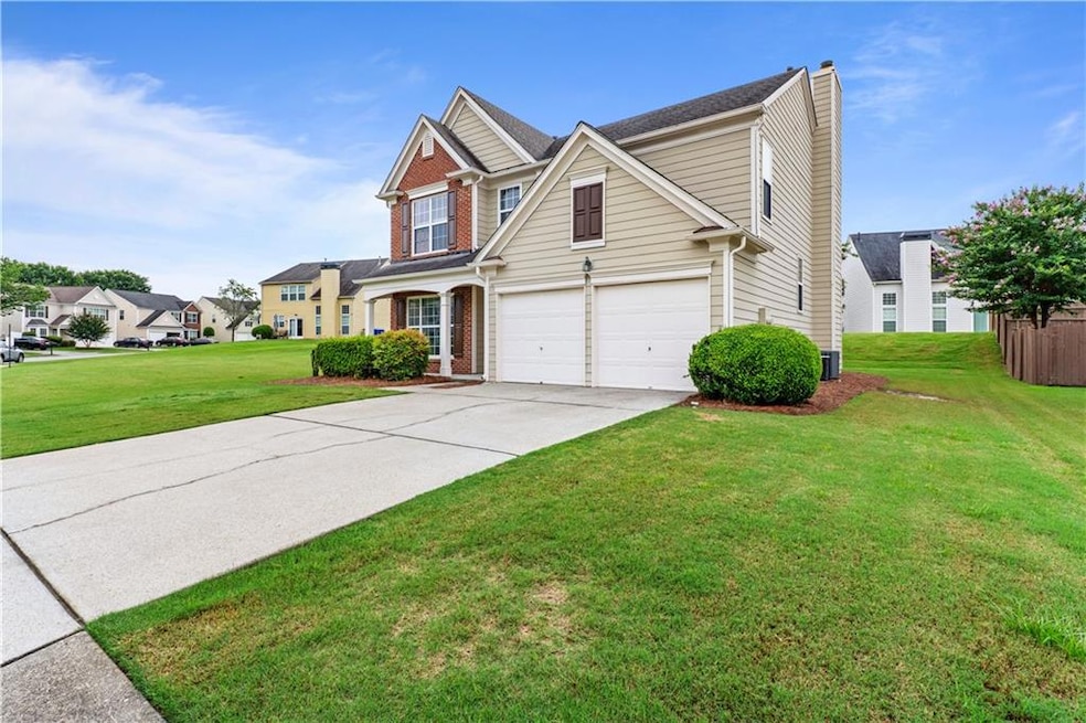 Traditional-style home with an attached garage, a chimney, driveway, a front lawn, and brick siding