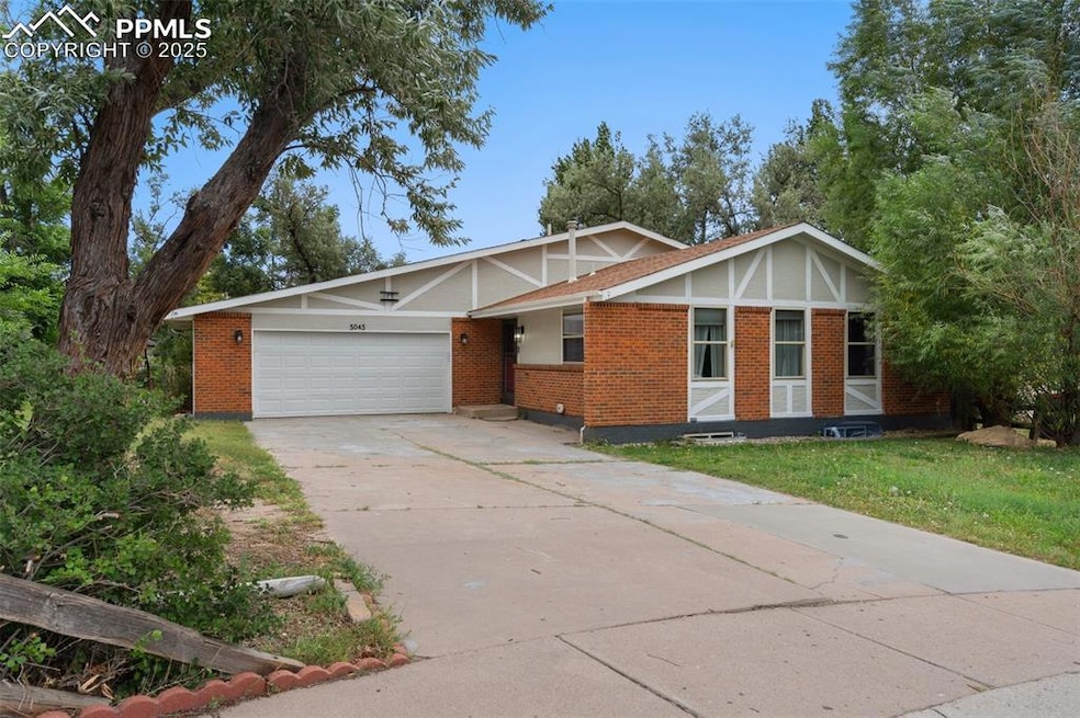 View of front of property with brick siding, driveway, and a garage