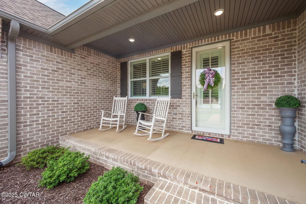 View of exterior entry featuring a porch, brick siding, and roof with shingles