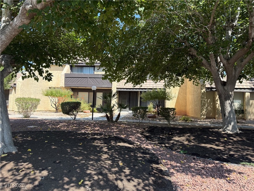 View of property hidden behind natural elements with stucco siding