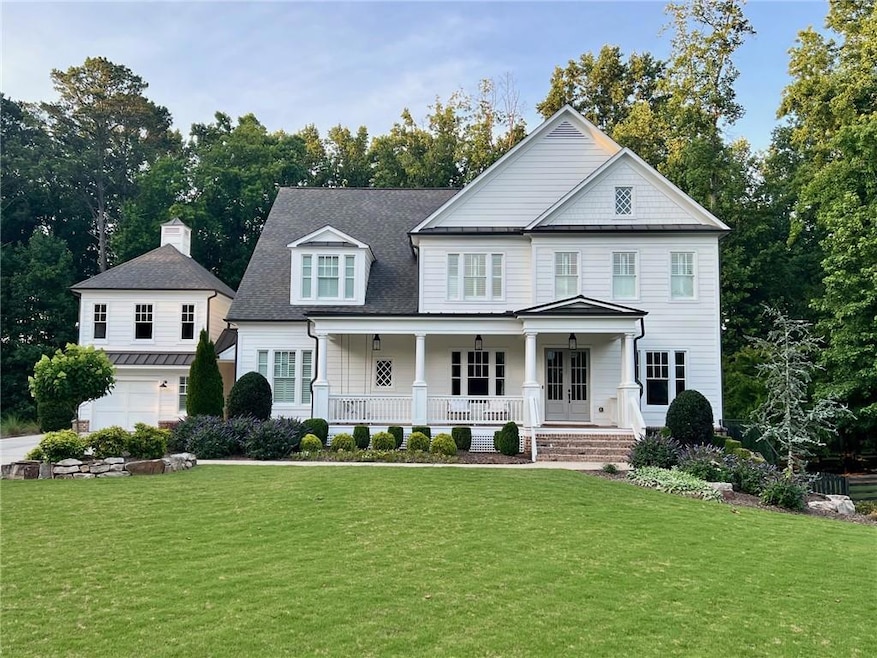 View of front of home featuring covered porch, a front yard, a garage, and a shingled roof