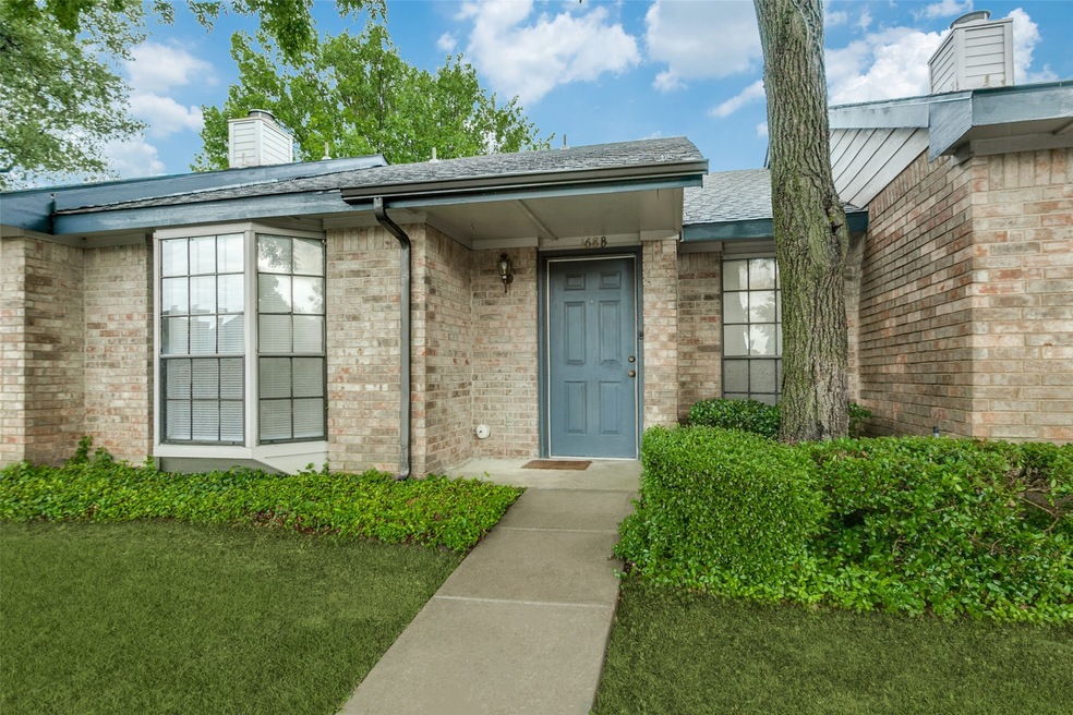 Doorway to property with brick siding, a yard, a chimney, and a shingled roof
