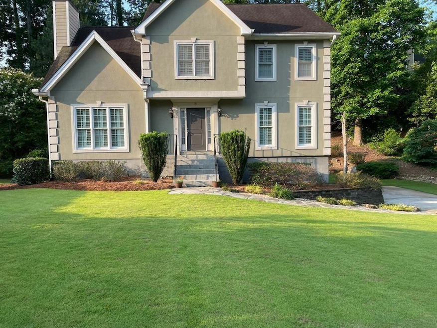 View of front facade featuring a chimney, a front yard, and stucco siding