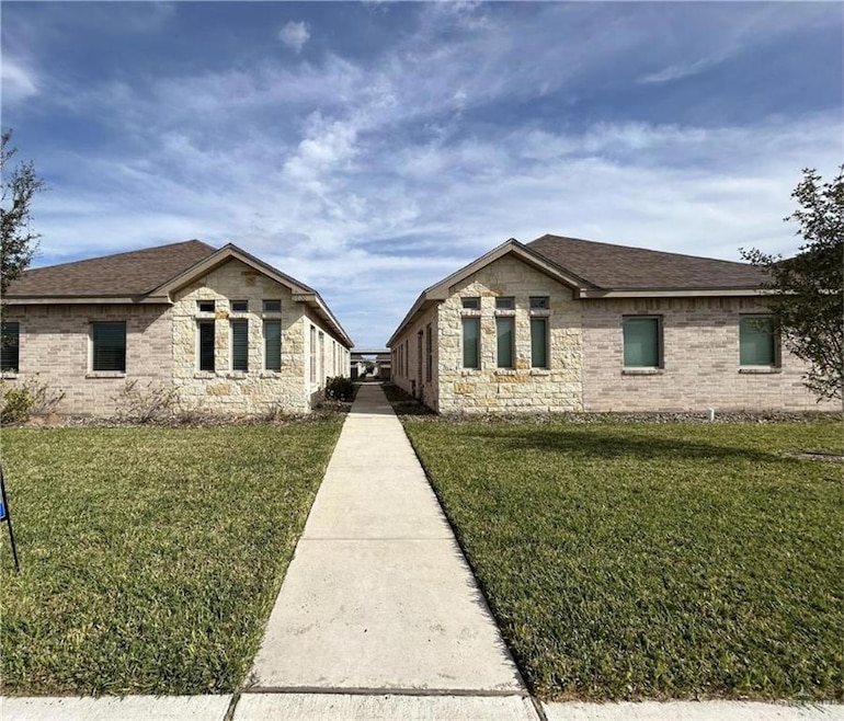 View of front facade with a front lawn, a shingled roof, and brick siding