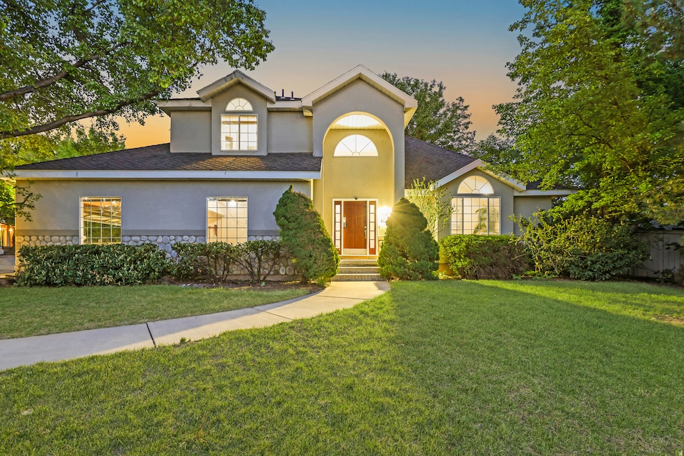View of front of property with a front yard, stucco siding, stone siding, and roof with shingles