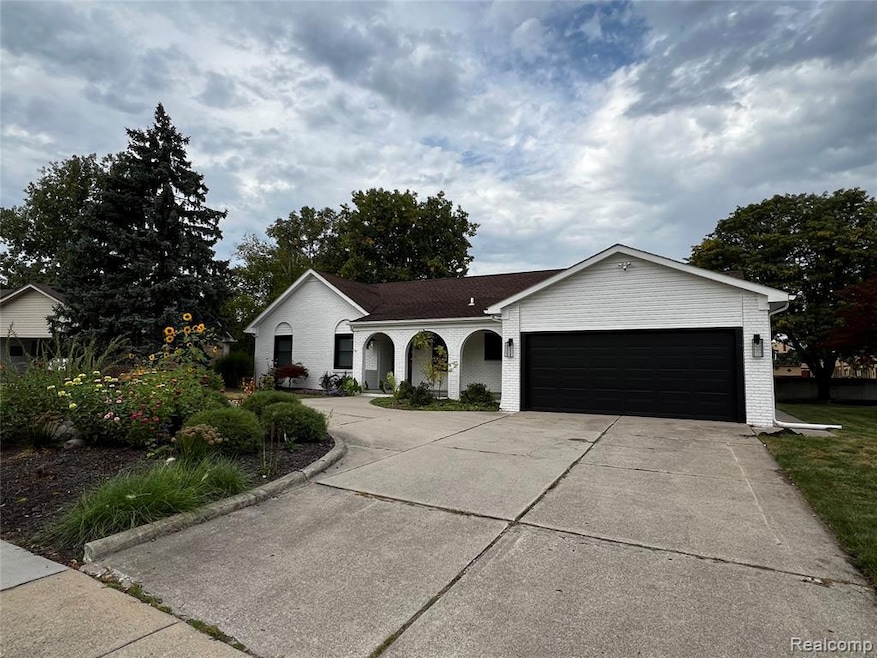 Ranch-style house featuring concrete driveway, covered porch, an attached garage, and brick siding