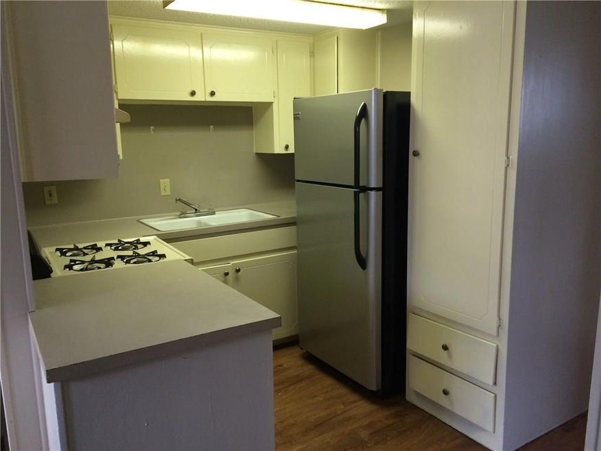 Kitchen featuring freestanding refrigerator, light countertops, dark wood-type flooring, white cabinetry, and white range with gas cooktop