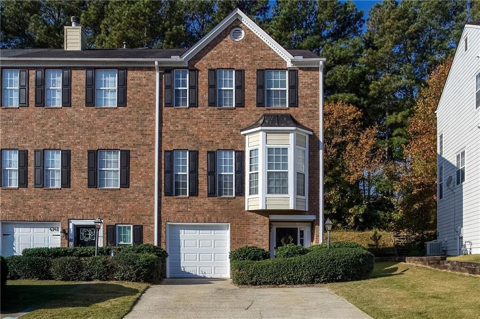 Colonial inspired home with concrete driveway, brick siding, a chimney, and a front lawn