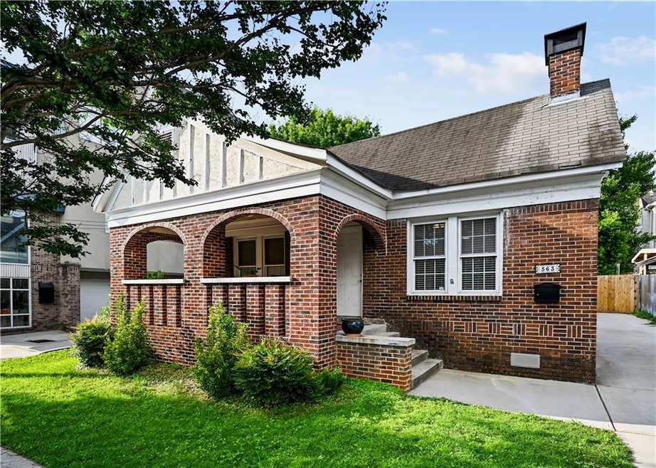 Tudor-style house with brick siding, a chimney, and a shingled roof