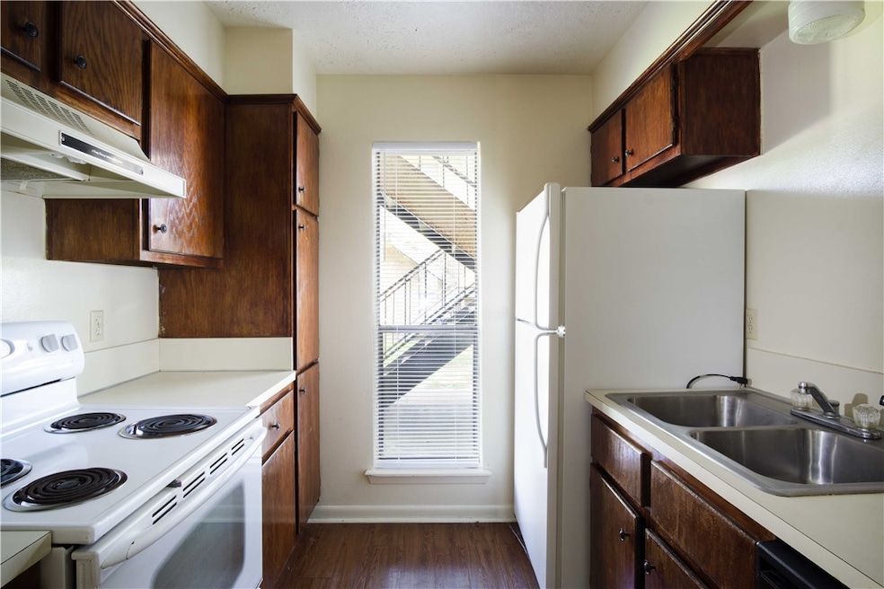 Kitchen with dark wood-style flooring, a sink, whi