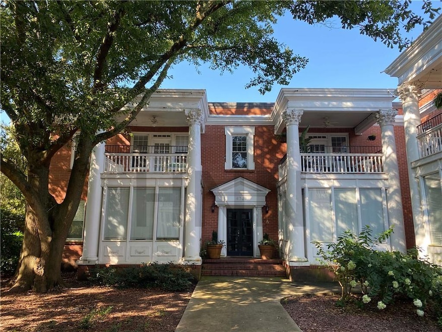 Neoclassical / greek revival house featuring a balcony, brick siding, and french doors