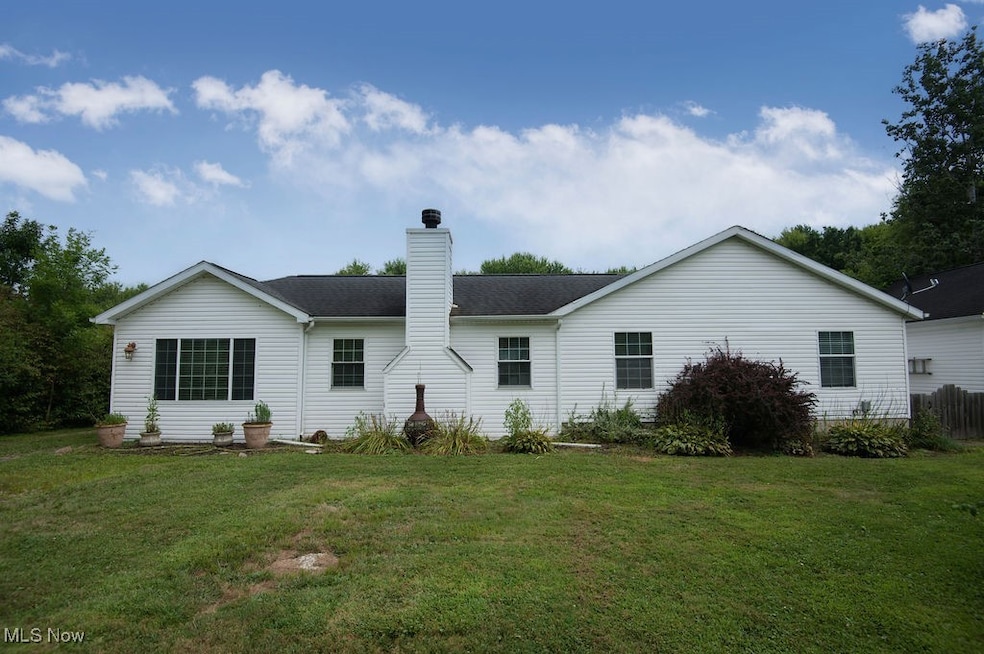 Front view of house with a chimney, a yard, and roof with shingles