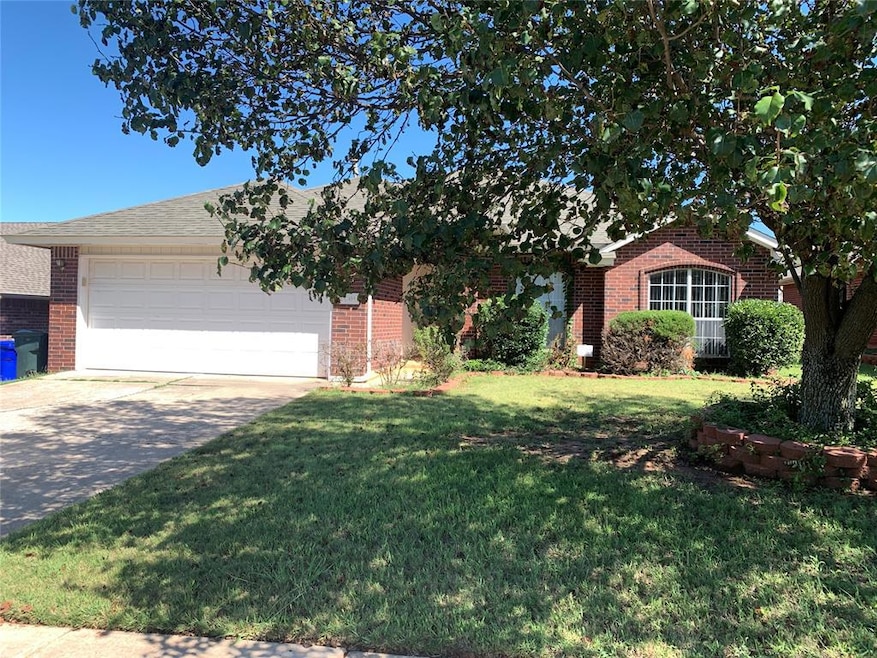 View of front of property with brick siding, concrete driveway, an attached garage, and a front yard