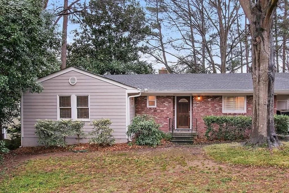 Single story home with entry steps, a shingled roof, brick siding, a chimney, and a front lawn