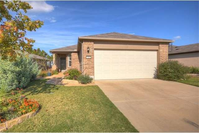 Backing a greenbelt flush with native trees, this Sun City Texas Gray Myst features beautiful planting beds, where colorful plants add seasonal allure.