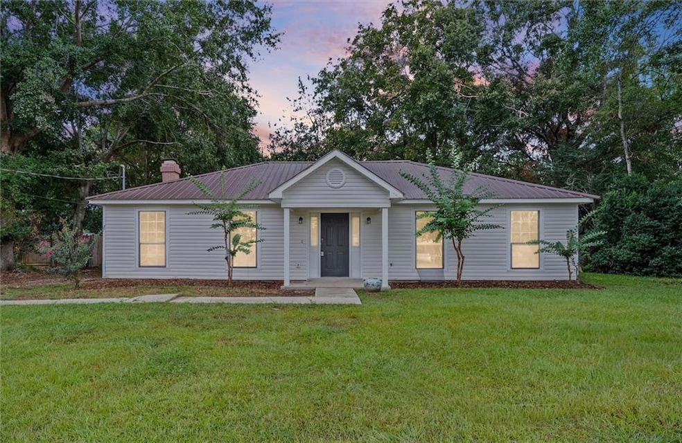 Single story home featuring a metal roof and a front lawn