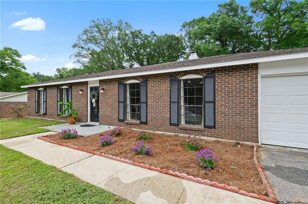 Ranch-style home with brick siding, a garage, a chimney, and driveway