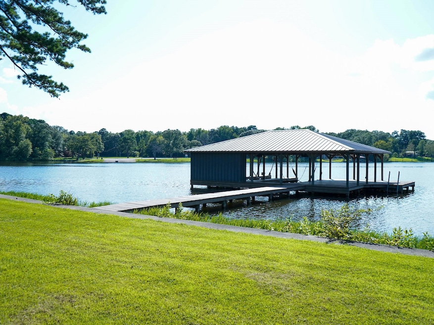 Dock area with a water view and a yard