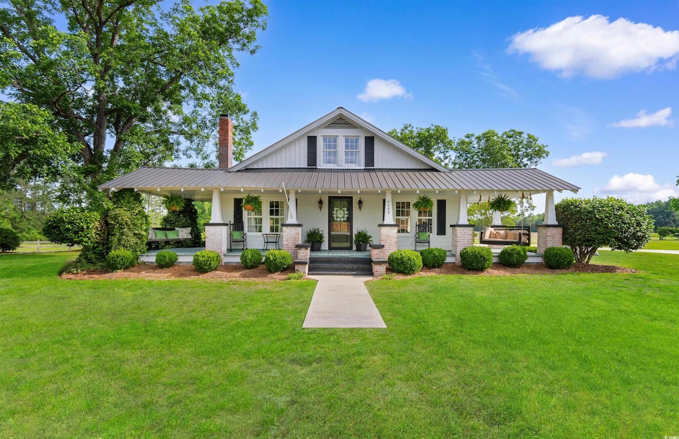 View of front of house with covered porch, metal roof, a front lawn, and a chimney